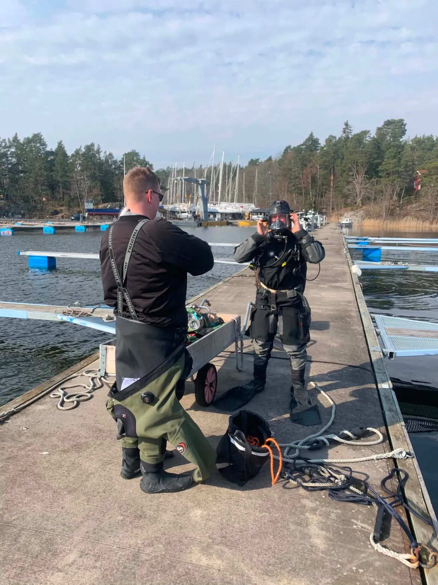 Två yrkesdykare gör sig klara på bryggan i en marina utanför Stockholm